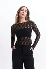 Remera negra de encaje floral con mangas largas, cuello redondo y corte ajustado. Incluye una capa interior opaca en el área del busto.