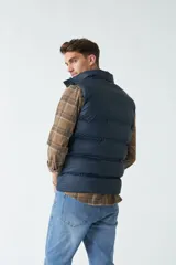 Chaleco color camel de nylon con cierre frontal con broches a presión, cuello alto y bolsillos laterales.