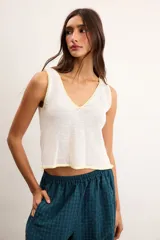 Musculosa de punto color blanco crudo, con escote en V y terminaciones con bordado artesanal amarillo.