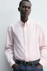 Camisa de corte regular fit confeccionada en tejido de algodón con diseño de rayas finas. Presenta cuello solapa, cierre frontal de botones y manga larga con puños abotonados.
