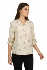 Blusa de viscosa color beige con estampado de tulipanes marrones, cuello en V con solapa y botones, manga 3/4 y un bolsillo frontal en el pecho.