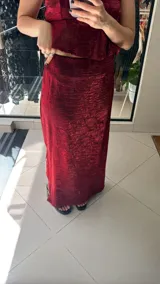 Falda midi de corte recto, confeccionada en tela satinada con textura arrugada en color bordó. Presenta un diseño elegante y fluido.