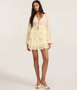 Blusa femenina de chiffon color amarillo pálido, con escote en V profundo, lazada ajustable en el centro del busto y mangas largas ajustadas. Presenta un diseño con volados en el ruedo.