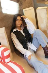 Top tipo chaleco confeccionado en tweed con apliques de lino que generan volumen y movimiento. Presenta un diseño frontal con cintas para atar y un ajuste entallado.