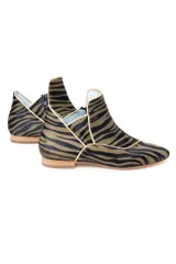 Botines de piel con diseño original, confeccionados artesanalmente en España. Presentan un estampado animal print en tonos verde y negro, con una estructura de piezas superpuestas y una pieza frontal elevada que estiliza el empeine. Cuentan con cierre lateral, interior forrado en piel y suela de cuero.