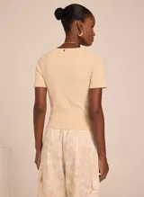 Remera color beige de tejido de punto acanalado, con cuello redondo y mangas cortas.