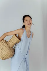 Vestido celeste de lino, corte recto, sin mangas y con lazo ajustable en la cintura.