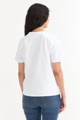 Remera de manga corta color beige, con estampa frontal en tono azul con la leyenda "New York 1990", de corte holgado y diseño casual.