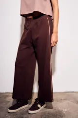 Pantalón deportivo de corte recto y holgado, confeccionado en algodón color marrón chocolate. Presenta una cintura elástica con cordón ajustable y una franja lateral decorativa en tono más claro.