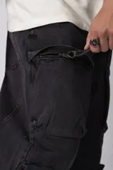 Jean baggy de corte holgado con múltiples bolsillos cargo frontales con cierre metálico. Presenta un acabado lavado, tiro medio y tiras de ajuste en la botamanga.