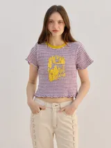 Remera baby-tee de algodón con textura fruncida, diseño a rayas violetas y blancas, cuello redondo amarillo y gráfico estampado en el frente.