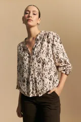 Camisa de manga larga con estampado abstracto en tonos marrón y beige, cuello mao con escote en V y botones frontales. Tiene puños elastizados y silueta relajada.