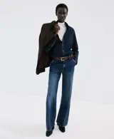 Jeans de tiro medio y corte wide leg, confeccionados en denim de algodón azul oscuro con lavado uniforme. Presentan cierre frontal con botón y cremallera, bolsillos laterales y traseros, y trabillas para cinturón.