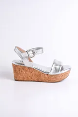 Sandalia plateada con plataforma de corcho, tira ancha sobre los dedos y pulsera con hebilla al tobillo.