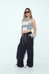 Pantalón tipo babucha de tiro bajo, color verde oliva, con silueta amplia y costuras visibles en contraste blanco. Posee cintura elástica con lazo blanco para ajuste.