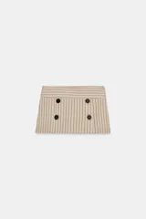 Falda pantalón de tiro bajo color beige con diseño de rayas diplomáticas verticales en tonos oscuros, con detalles de cuatro botones negros decorativos en la parte frontal y cierre lateral con cremallera oculta.