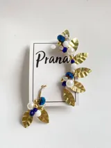 Par de aros trepadores con base dorada y diseño de hojas, perlas y cuentas de cristal blancas y azules.