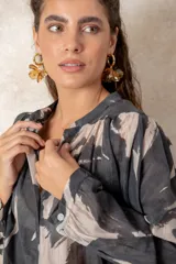 Camisa oversize con estampado abstracto en tonos marrones y beige, cuello mao y cierre frontal con botones. Presenta mangas largas anchas con puños abotonados y un corte holgado.