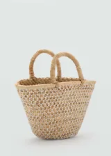 Bolso tipo canasta de tamaño pequeño, confeccionado en fibra natural trenzada con un diseño de red superpuesto en color blanco. Cuenta con dos asas cortas de mano y una estructura abierta sin cierre.