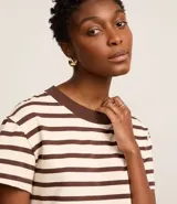 Remera de corte boxy confeccionada en algodón, con diseño de rayas horizontales en blanco y negro, cuello redondo en color negro contrastante y mangas cortas.