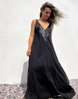 Vestido largo de corte holgado en color negro, con escote en V profundo decorado con lentejuelas negras brillantes. Presenta un diseño sin mangas y una caída fluida.