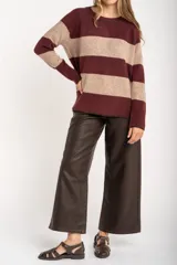 Sweater de punto con diseño de rayas horizontales anchas en color bordó y beige. Presenta cuello redondo con detalle de lurex, mangas largas y puños y ruedo acanalados.