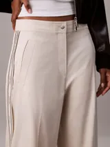 Pantalón de sarga color beige, de corte regular y pierna ancha, con franjas laterales con el logo de Calvin Klein y bolsillos laterales.