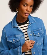 Campera trucker de jean azul oscuro, con cuello inglés, abotonado delantero, bolsillos con solapa y manga larga.