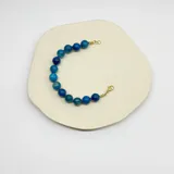 Pulsera de cuentas de ágata azul de 10 mm, con separadores de nudos de hilo azul y cierre de mosquetón con baño de oro.