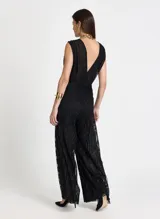 Pantalón de tiro alto con corte de pierna ancha y caída fluida. Confeccionado en tejido de punto con textura brillante y sutil transparencia, presenta una cinturilla ancha estructurada con un ligero fruncido bajo la misma y bajo recto.