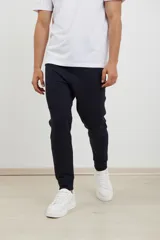 Pantalón jogging de corte slim, con puños elastizados, cintura con cordón ajustable, cierres laterales engomados y bolsillo tipo parche lateral.