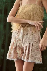 Shorts de brocato con estampado floral en tonos rosados y beige, con terminación de flecos en el ruedo.