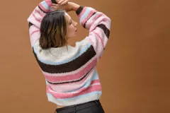 Sweater de punto con diseño de rayas horizontales en tonos rosa, celeste, blanco y marrón. Presenta cuello redondo y mangas largas con corte holgado.