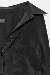 Camisa de corte amplio y fluido con cuello solapa, manga larga con puños abotonados y bolsillo de plastrón en el delantero. Presenta cierre frontal con botones y un acabado satinado.