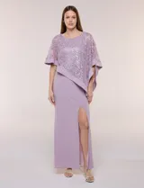 Vestido largo azul marino de seda fría, compuesto por una falda recta con tajo frontal y una capa superior superpuesta de encaje con lentejuelas bordadas, escote a la base y mangas tres cuartos acampanadas.
