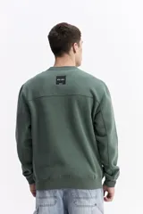 Buzo de algodón color marrón chocolate, con cuello redondo, mangas largas y estampa frontal con el nombre de la marca repetido en tono sobre tono.