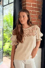 Blusa de lino color beige, con detalle de tejido crochet en la parte superior del frente y mangas abullonadas con puños elastizados y volados.