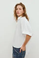 Camisa de manga corta y corte fluido, color marrón, con cuello solapa y cierre frontal con botones ocultos. Presenta bajo asimétrico con aberturas laterales y mangas con vuelta.