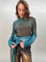 Buzo de punto confeccionado en 100% lana merino con efecto degradé en tonos azules. Presenta un diseño versátil con lazos largos que nacen de la cintura alta para anudar de diferentes formas, mangas entalladas con ojal para el pulgar y cuello redondo.