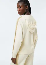 Campera de punto con cierre frontal, capucha con cordones ajustables y bolsillos tipo canguro. Presenta un diseño de manga larga con detalles acanalados en los laterales y puños.
