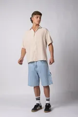 Camisa de manga corta confeccionada en lino, con cuello clásico y cierre frontal de botones. Presenta un corte relajado y textura liviana.