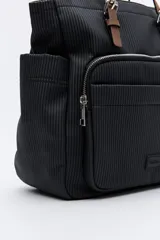 Mochila negra de poliéster texturizado con superficie acanalada. Cuenta con asas superiores marrones, tiras regulables para la espalda, bolsillo frontal con cierre metálico, compartimentos laterales y un interior amplio.