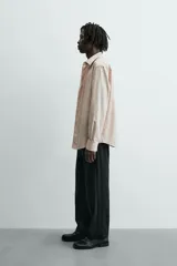 Camisa slim fit color beige, confeccionada en tejido de algodón, con cuello italiano y manga larga con puño de botón. Cierre frontal de botonadura.