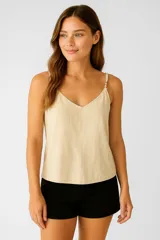 Musculosa de viscosa color beige, con escote en V, breteles finos ajustables con detalle de cuentas y aro decorativo en el hombro.
