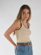 Musculosa color beige con ribetes negros y detalles bordados en el cuello y las sisas.