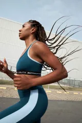 Top deportivo azul con contorno blanco y banda inferior negra con la inscripción "LOLITA ACTIVEWEAR" en blanco.