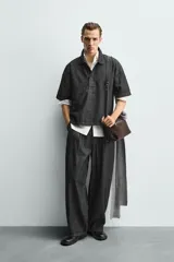 Camisa de manga corta con cuello solapa y cierre frontal de botones. Confeccionada en tejido denim de algodón, de corte relajado y aberturas laterales en el bajo.