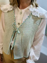 Chaleco con estampado geométrico en tonos turquesa y beige, con escote en V y lazo para ajustar en la parte delantera. Confeccionado en lino italiano reversible.