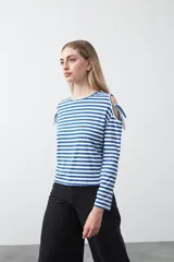 Remera de manga larga con estampado de rayas horizontales en azul y blanco, cuello redondo y aberturas tipo cut out en los hombros con lazos ajustables.