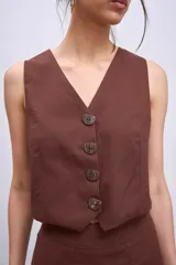 Chaleco corto de corte sastrero en color marrón, con escote en V y cierre frontal con botones a tono.